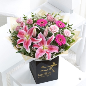Pink lilies, germini, roses and lisianthus hand tied with white gyp.